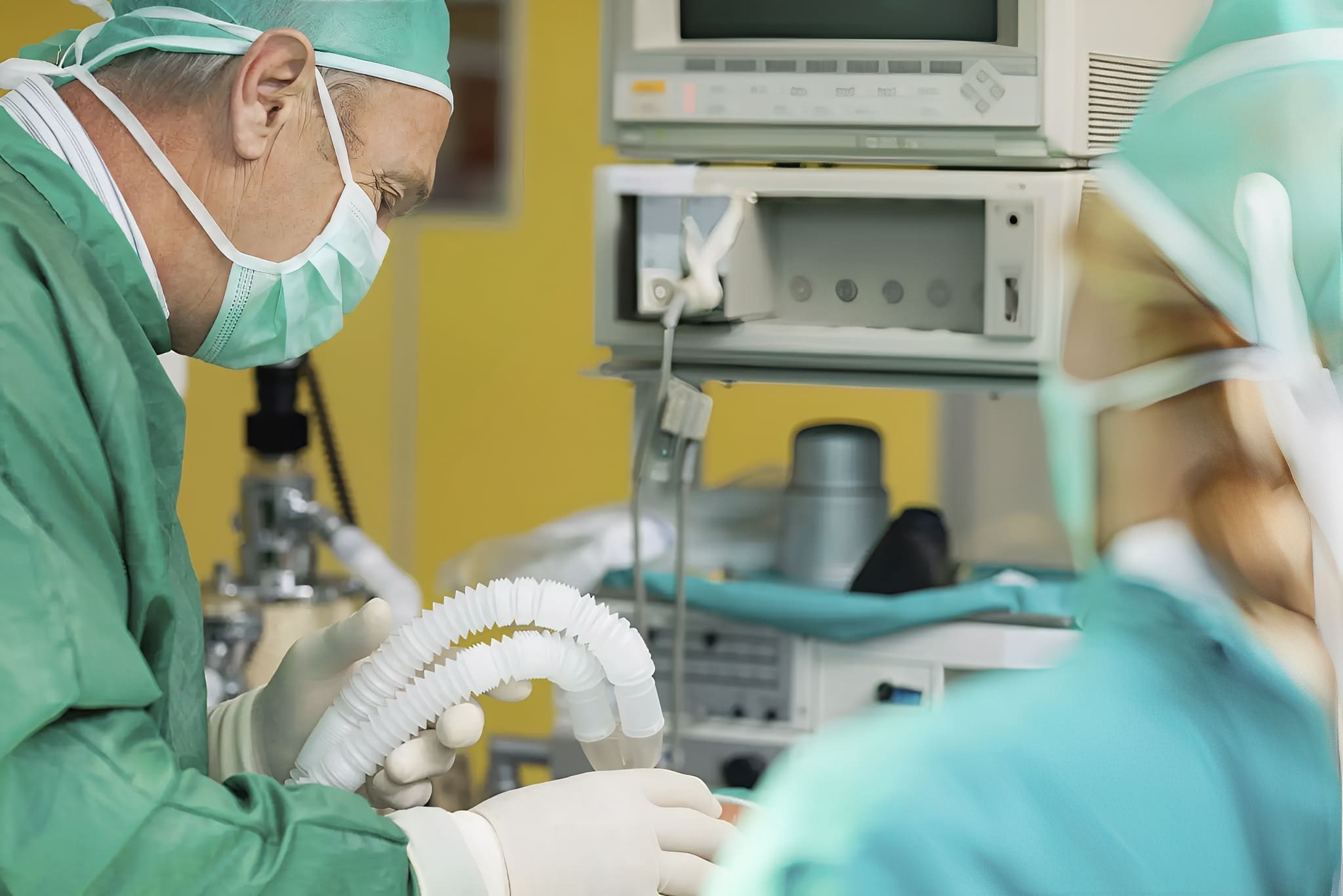 Surgeons in operating room with medical equipment.